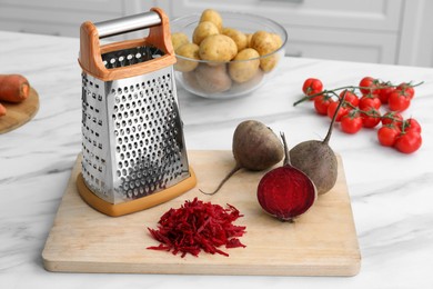 Grater and fresh ripe beetroots on white marble table