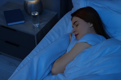 Beautiful young woman sleeping in bed at night