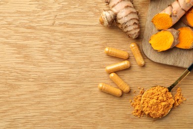 Photo of Aromatic turmeric powder, raw roots and pills on wooden table, flat lay. Space for text