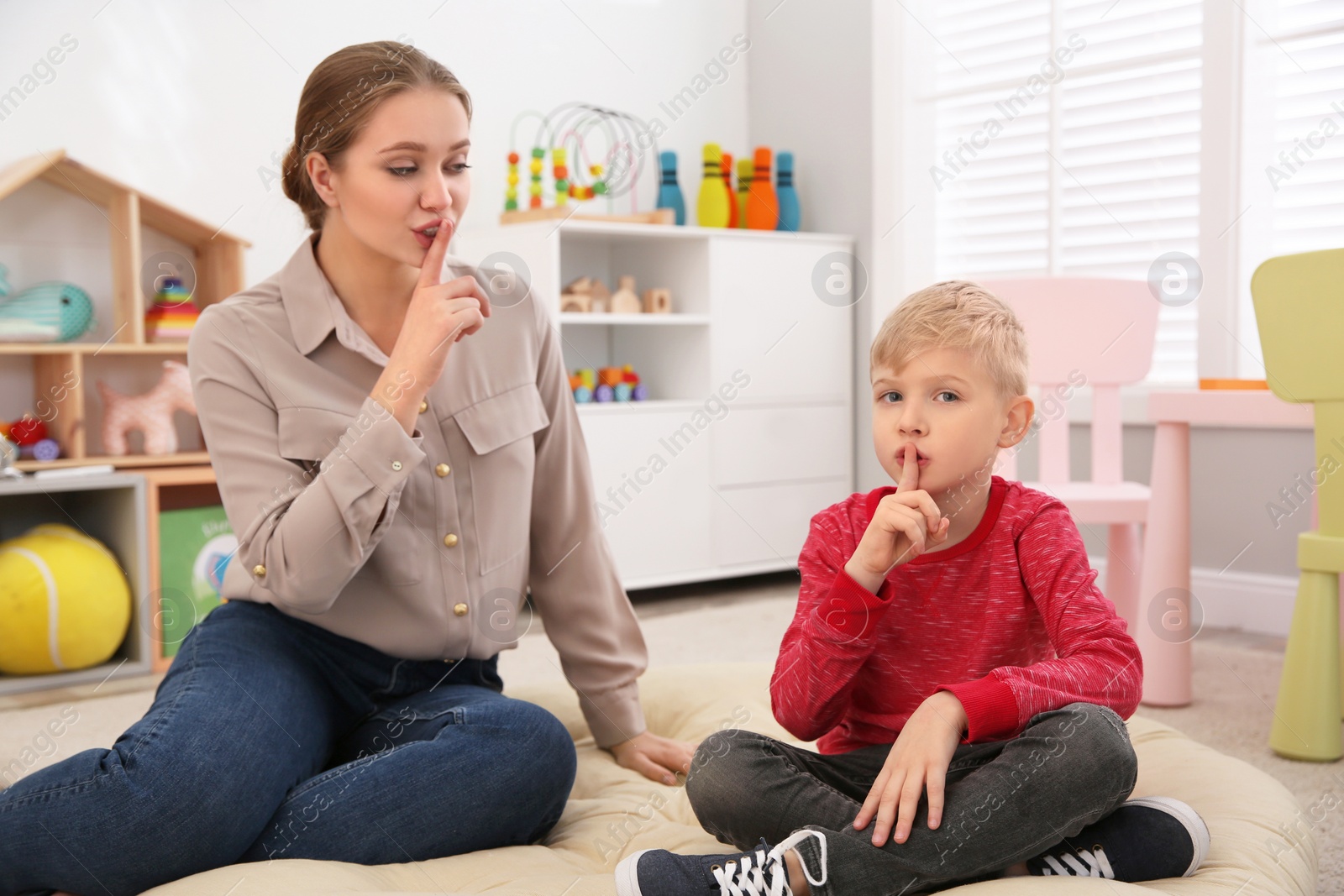 Photo of Speech therapist working with little boy in office