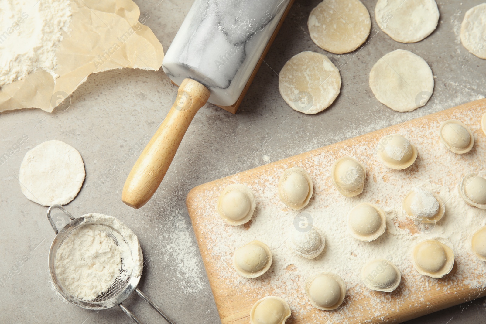 Photo of Flat lay composition with raw dumplings on grey background. Process of cooking