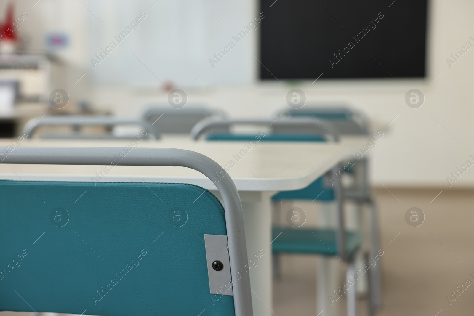 Photo of Empty school classroom with desks, blackboard and chairs