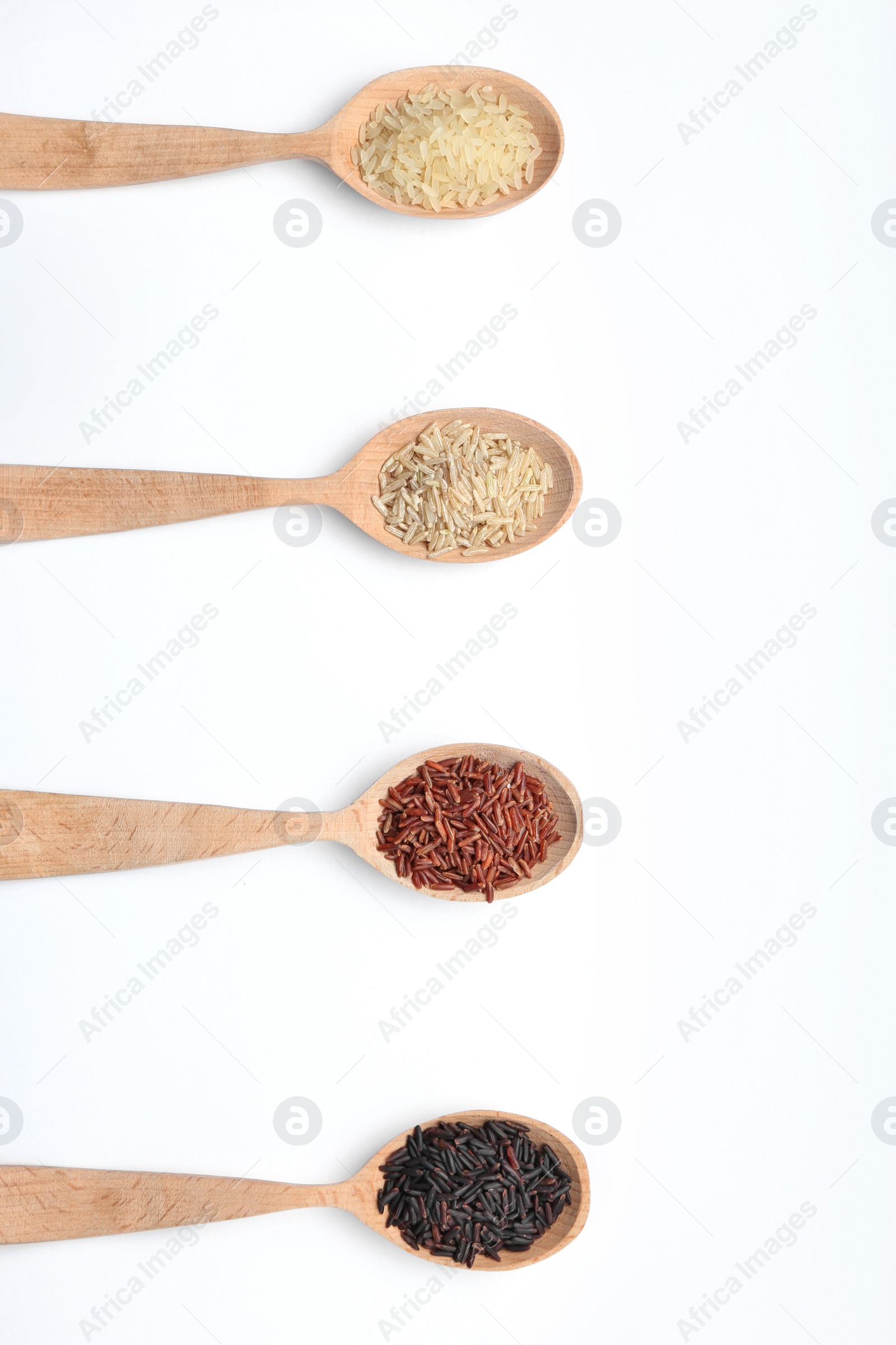 Photo of Spoons with different types of uncooked rice on white background, top view