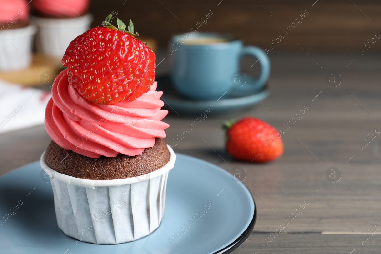 Photo of Sweet cupcake with fresh strawberry on wooden table. Space for text