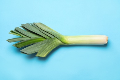 Photo of Fresh raw leek on light blue background, top view. Ripe onion
