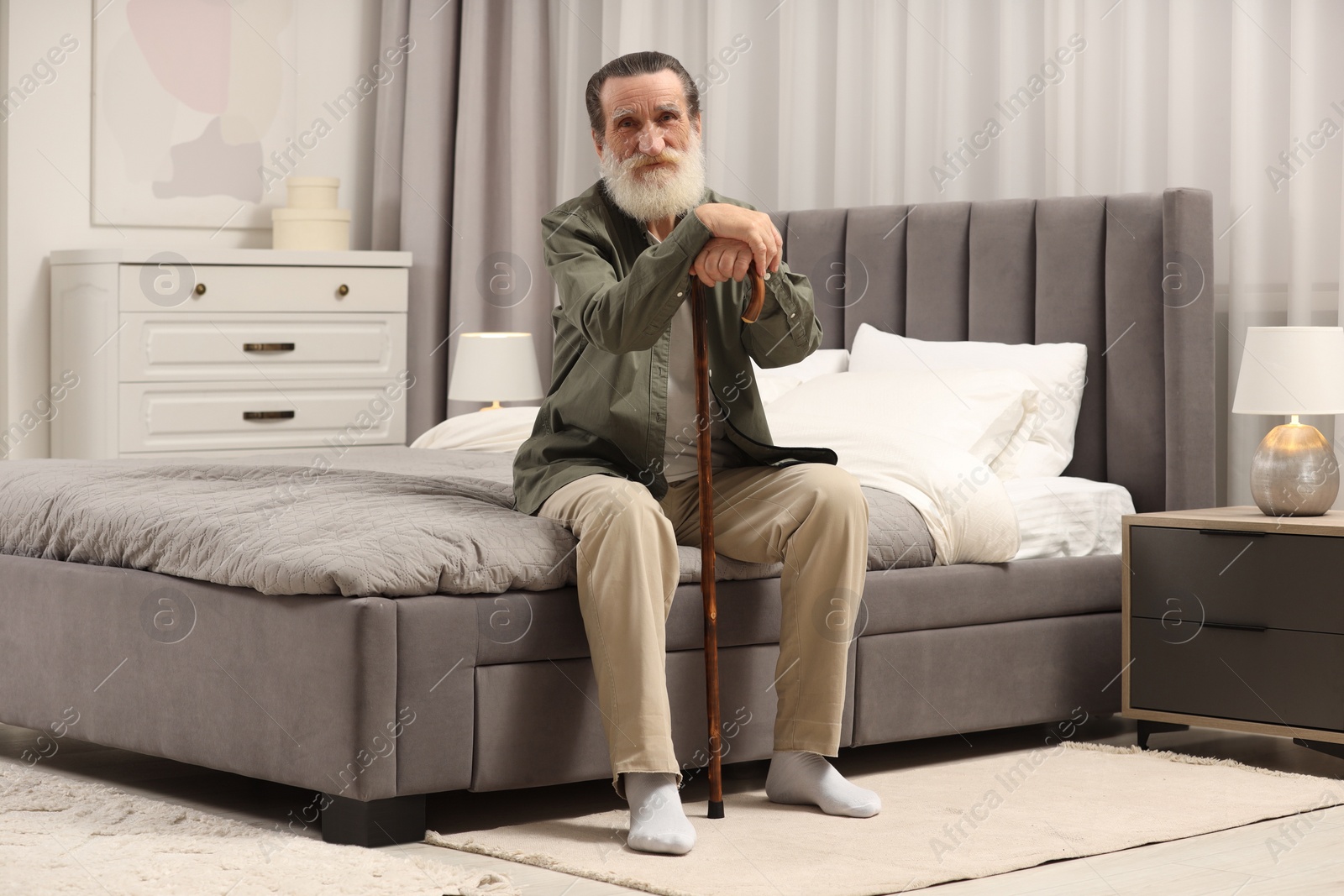 Photo of Senior man with walking cane on bed at home