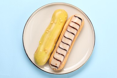 Photo of Delicious eclairs covered with glaze on light blue background, top view