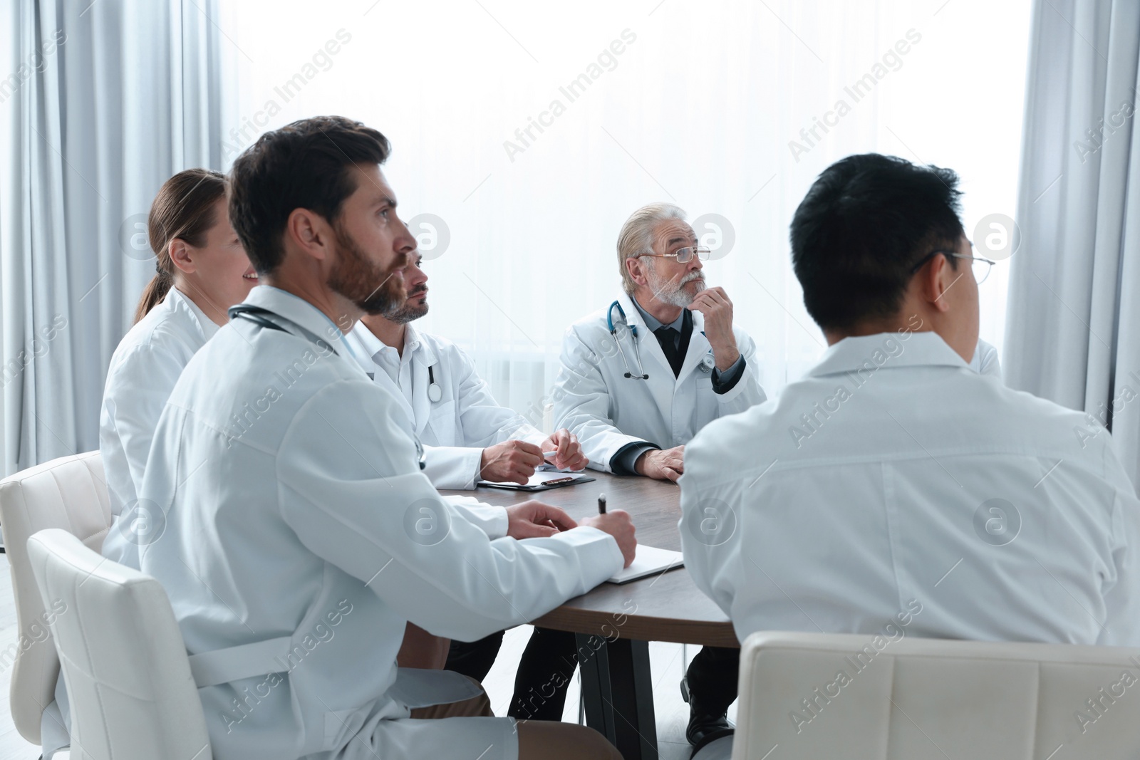 Photo of Team of doctors watching presentation in room. Medical conference