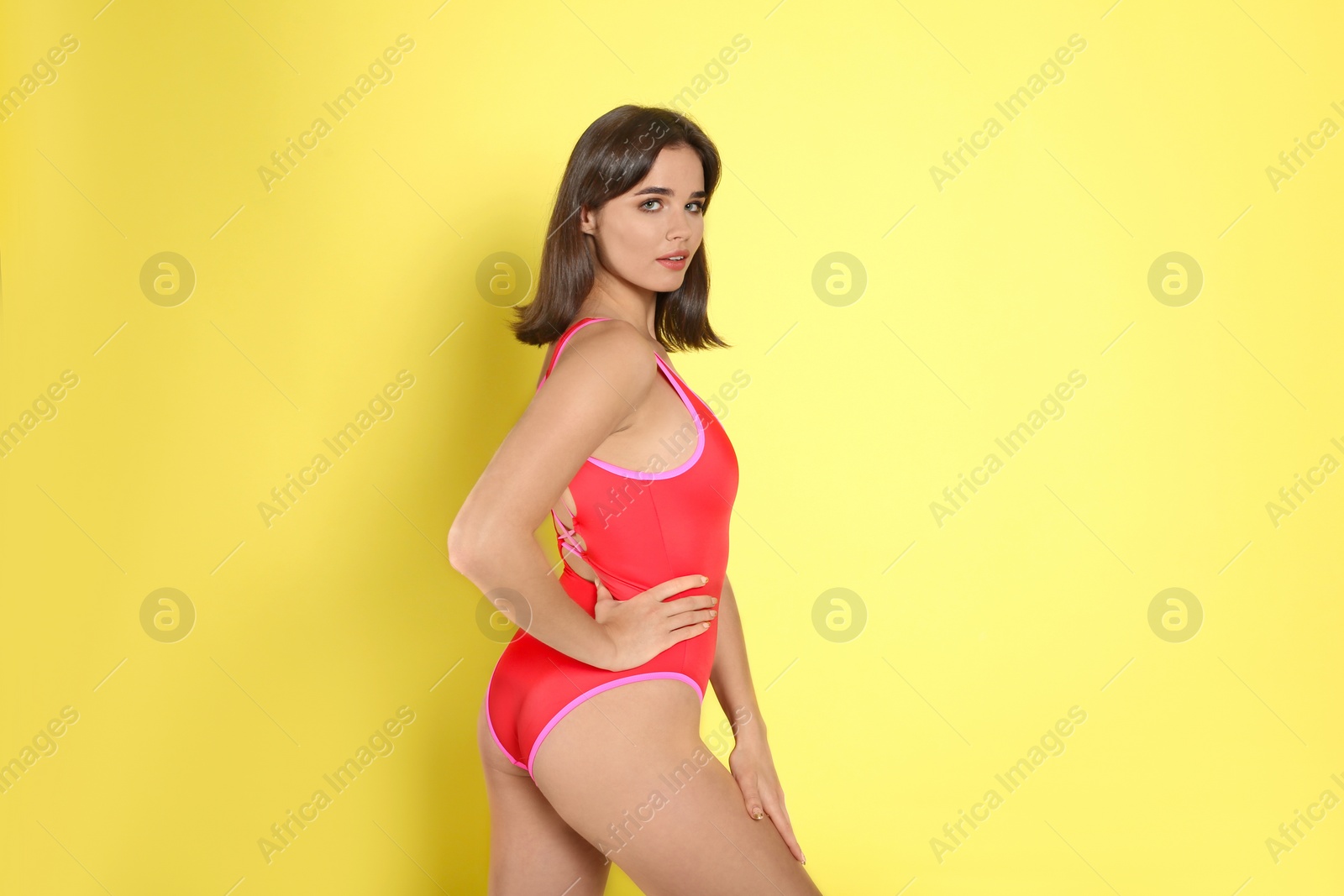 Photo of Beautiful woman in red swimsuit on yellow background