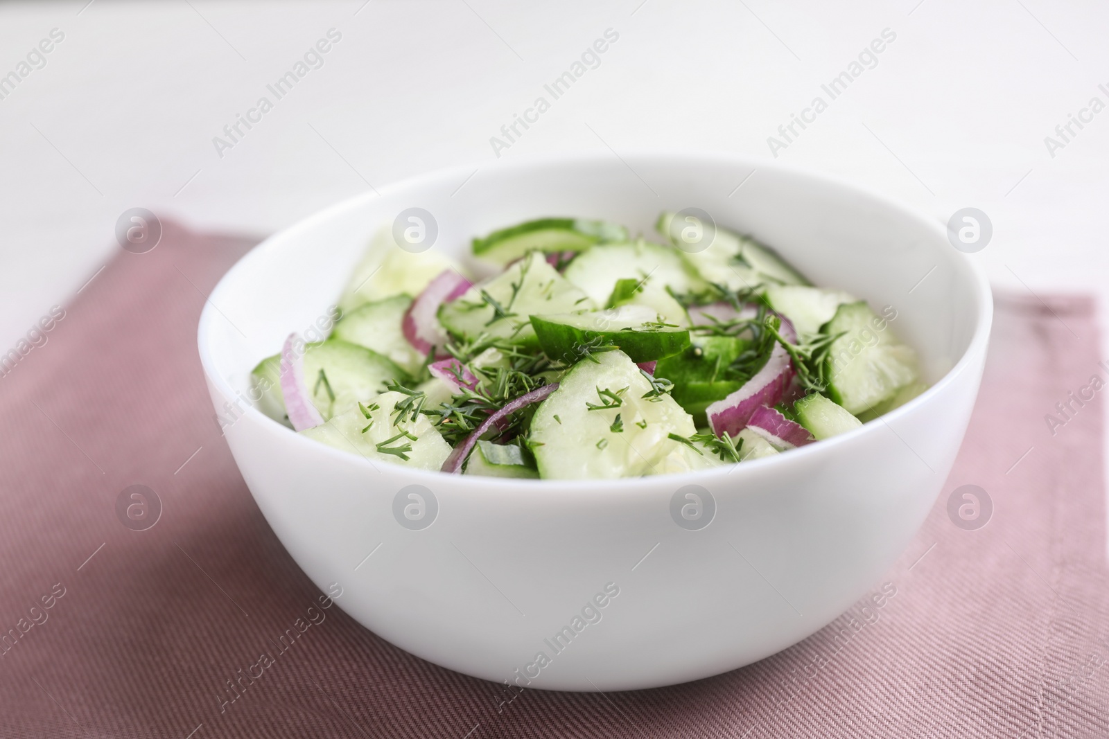 Photo of Delicious fresh cucumber onion salad in bowl served on table