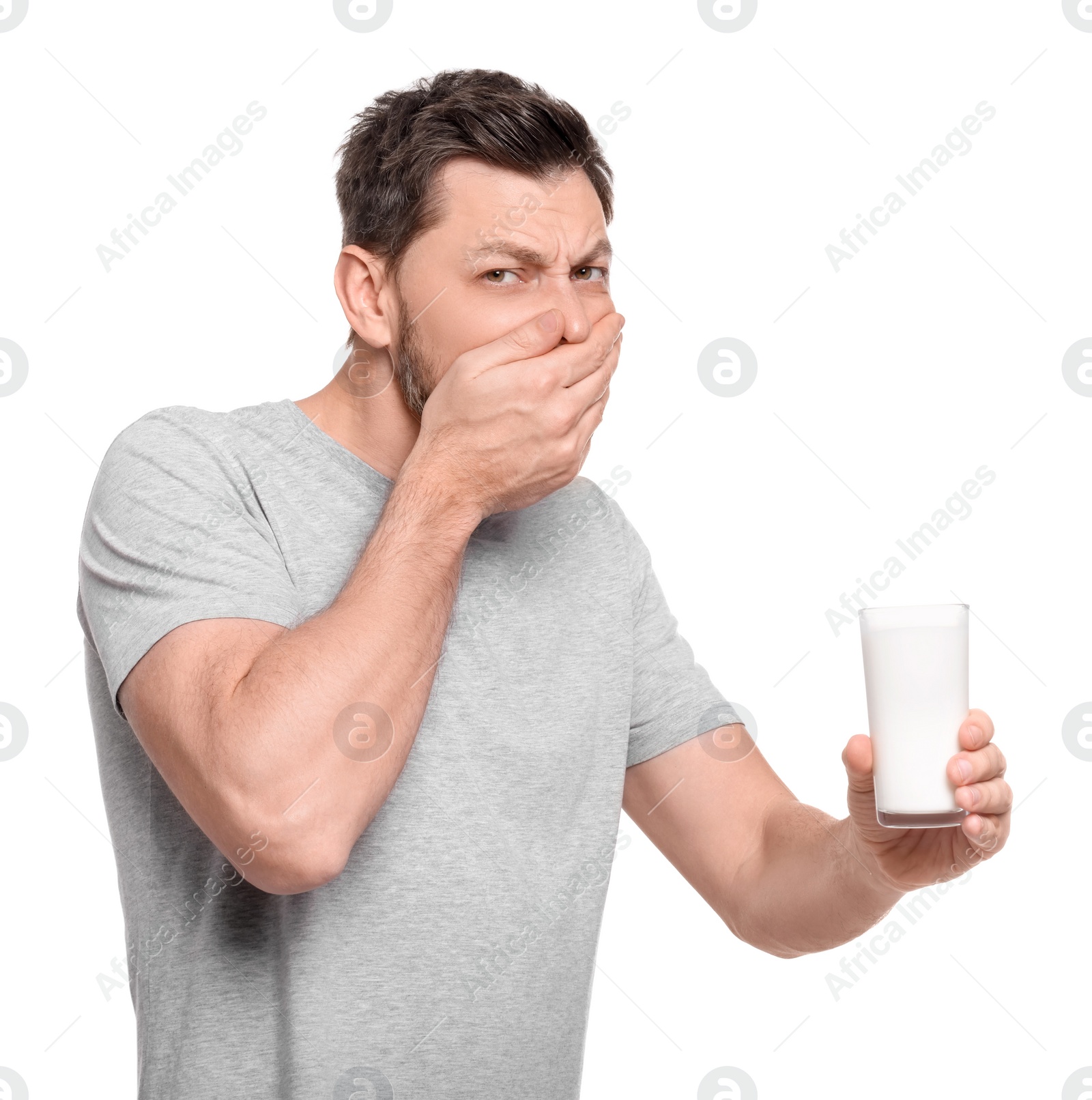 Photo of Man with glass of milk suffering from lactose intolerance on white background