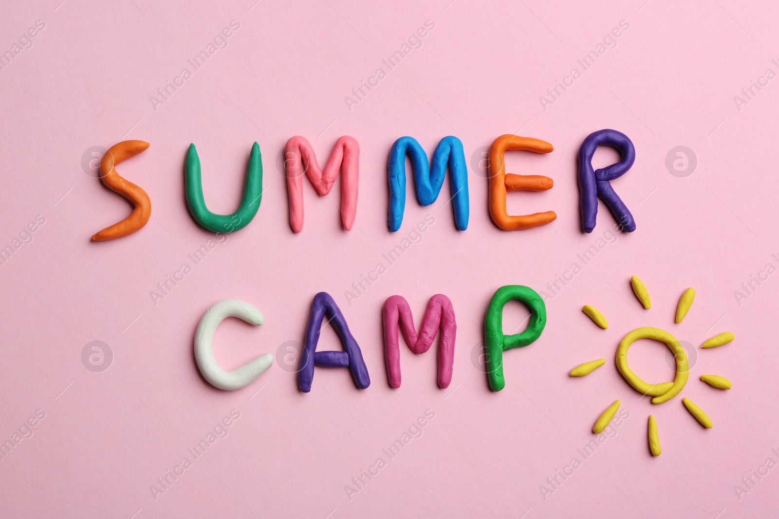 Photo of Phrase SUMMER CAMP made of colorful clay on pink background, flat lay