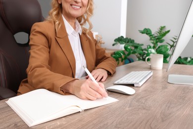 Photo of Lady boss working near computer at desk in office, closeup. Successful businesswoman