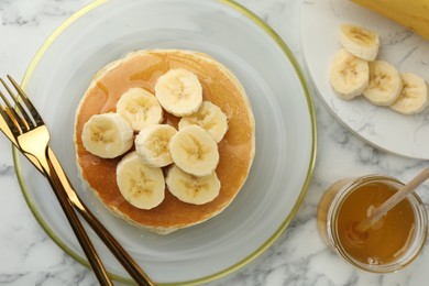 Photo of Delicious pancakes with bananas and honey served on white marble table, flat lay