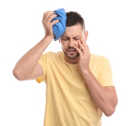 Unhappy man using cold pack to cure headache on white background