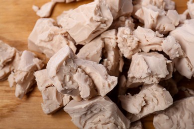 Pieces of compressed yeast on wooden board, top view