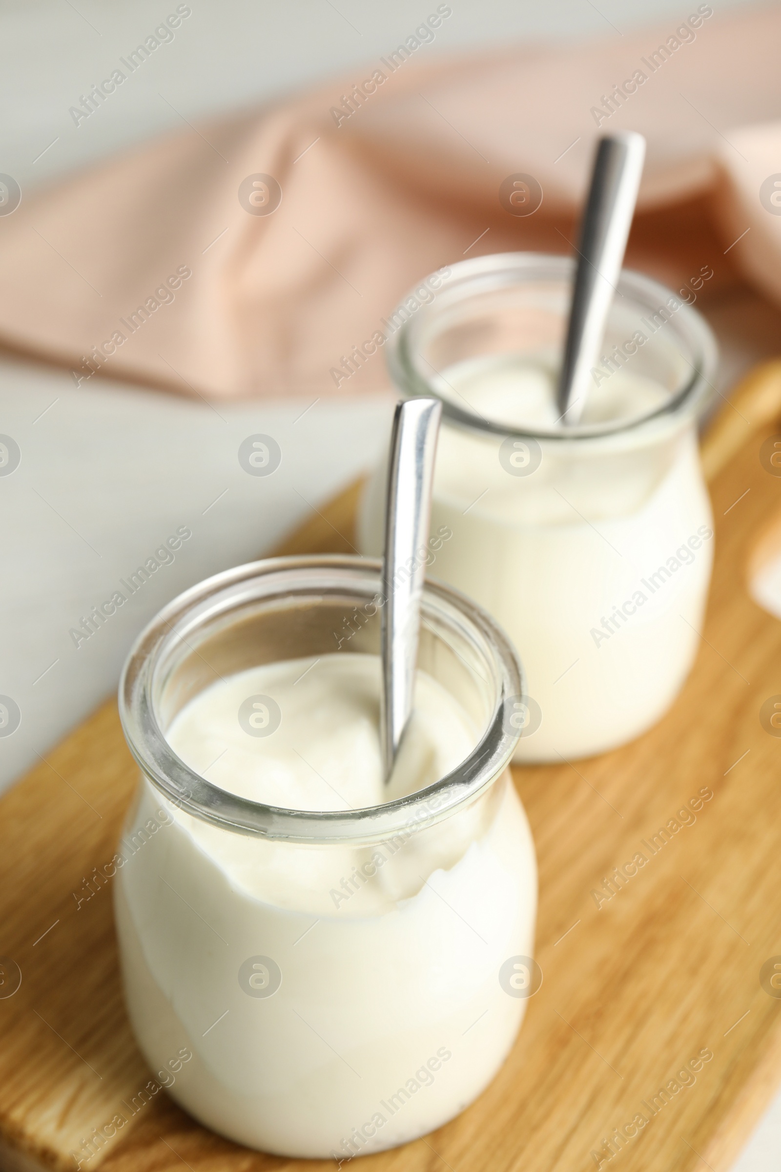 Photo of Tasty organic yogurt in glass jar on wooden board