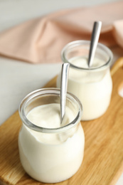 Photo of Tasty organic yogurt in glass jar on wooden board