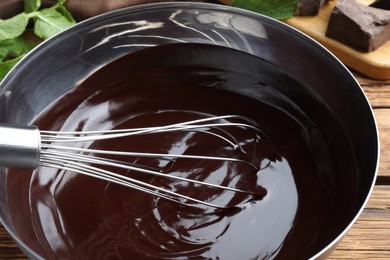 Delicious chocolate cream and whisk in bowl on table, closeup