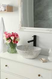 Photo of Vase with beautiful pink tulips near sink in bathroom