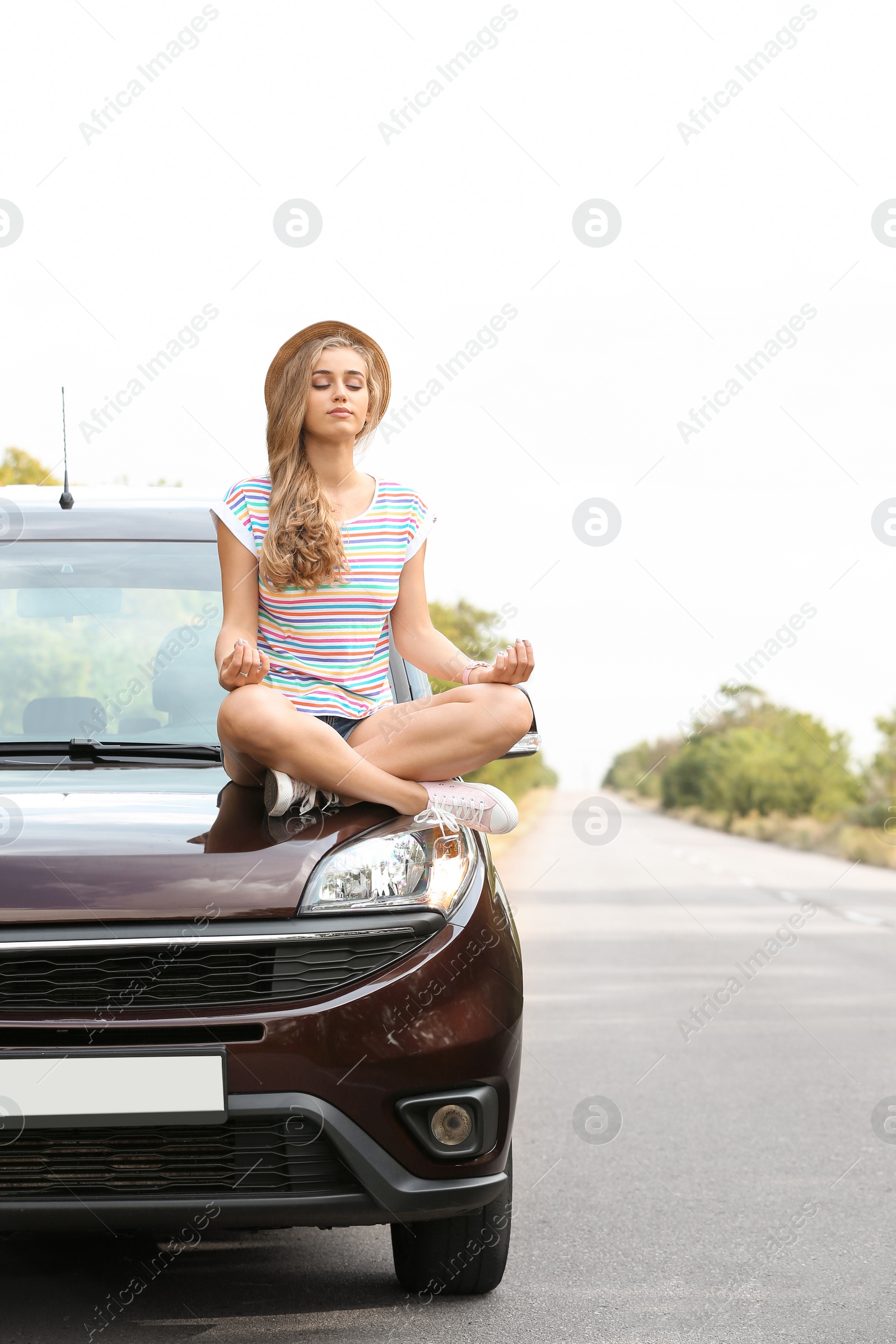 Photo of Young woman meditating on car hood outdoors. Joy in moment