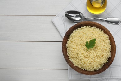 Tasty couscous with parsley on white wooden table, top view. Space for text