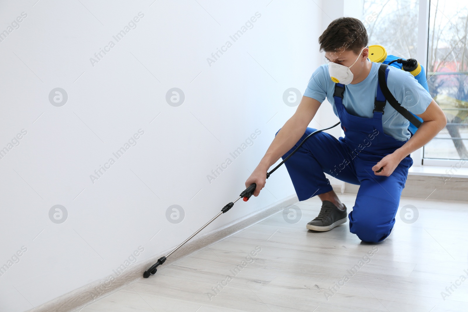 Photo of Pest control worker spraying pesticide in room. Space for text