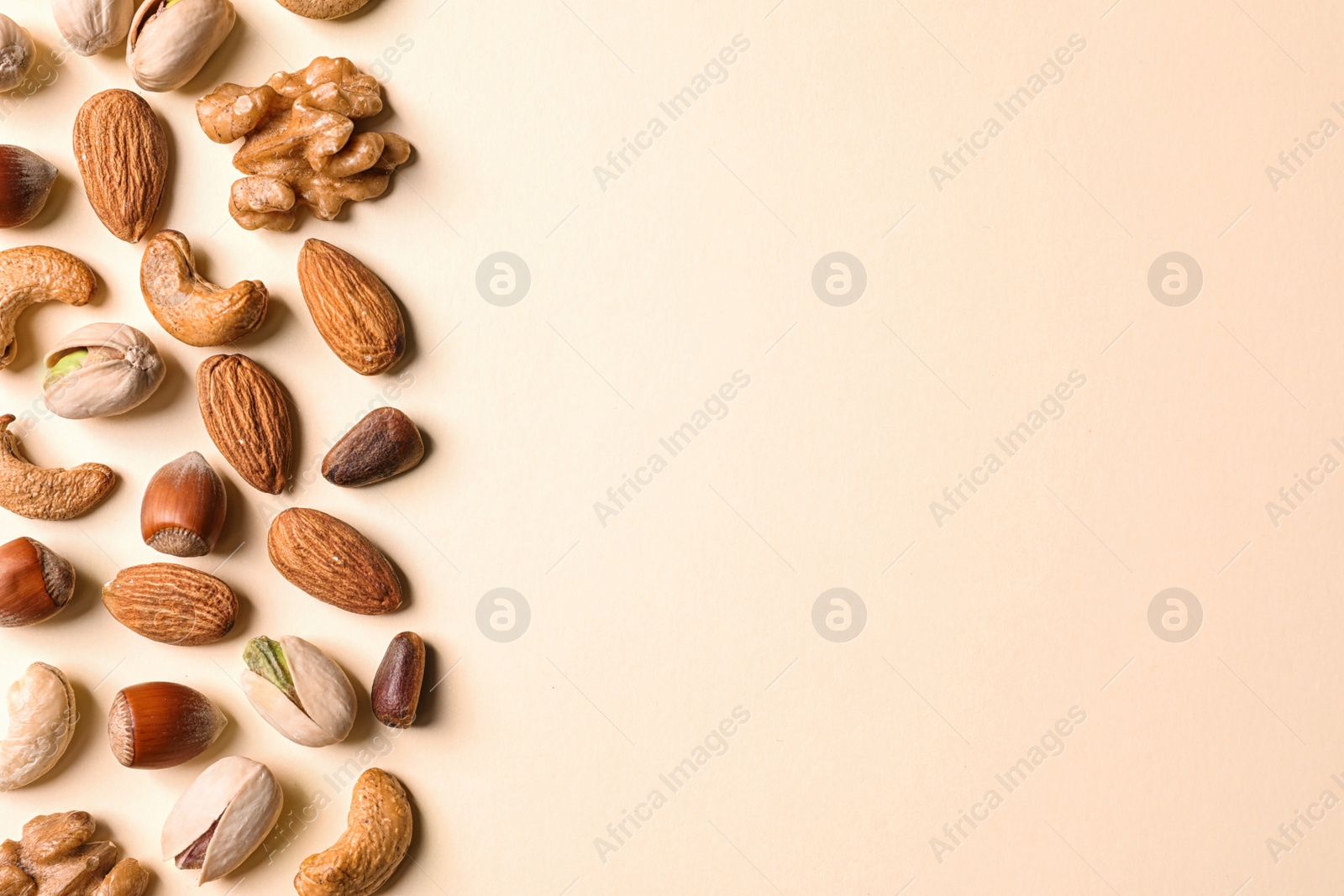 Photo of Flat lay composition with organic mixed nuts and space for text on color background