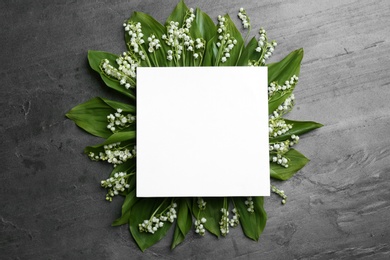 Blank card with lily of the valley flowers on grey background, top view. Space for text