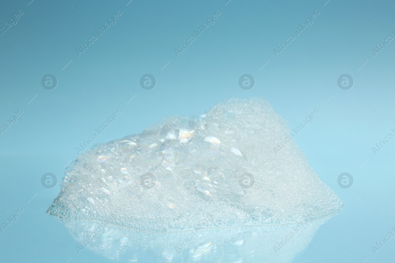 Photo of Drop of fluffy bath foam on turquoise background