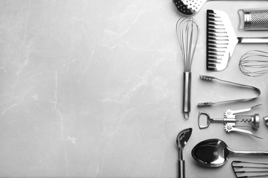 Different kitchen utensils on grey background, top view with space for text