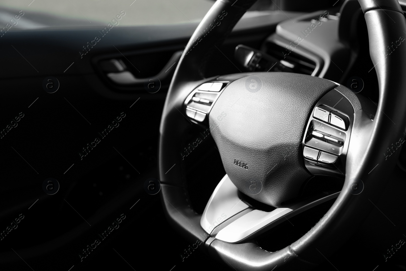 Photo of Black steering wheel inside of modern car, closeup. Space for text