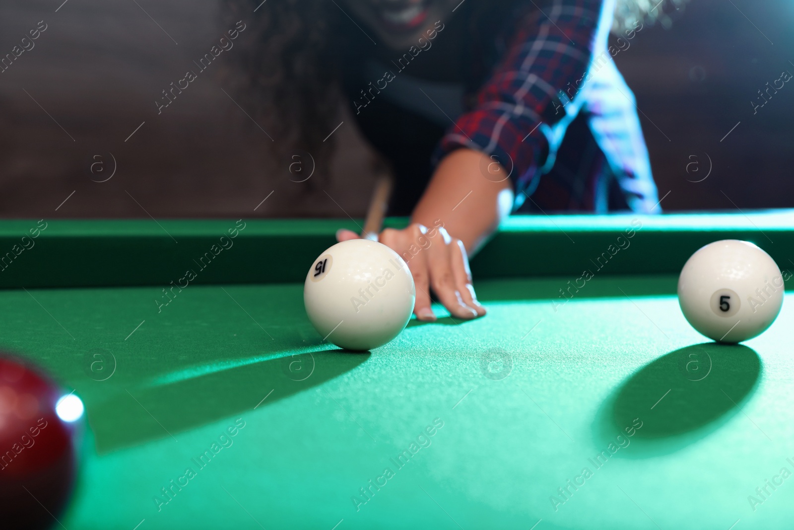 Photo of Young African-American woman playing billiard indoors, closeup