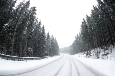 Beautiful landscape with conifer forest and road on snowy winter day