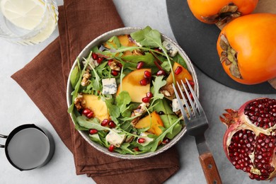 Photo of Tasty salad with persimmon, blue cheese, pomegranate and walnuts served on light grey table, flat lay