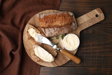 Photo of Tasty bread with butter and knife on wooden table, top view