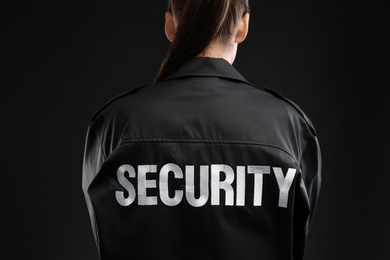 Photo of Female security guard in uniform on dark background, closeup