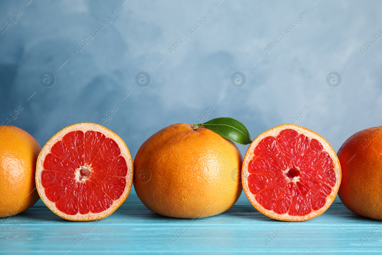 Photo of Fresh tasty grapefruits on table against color background. Space for text