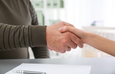 Lawyer shaking hands with client in office, closeup