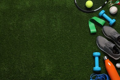 Photo of Different sport tools on green grass, flat lay. Space for text