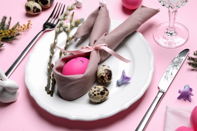 Festive Easter table setting with eggs on pink background