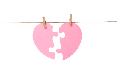 Photo of Halves of paper heart hanging on rope against white background. Relationship problems