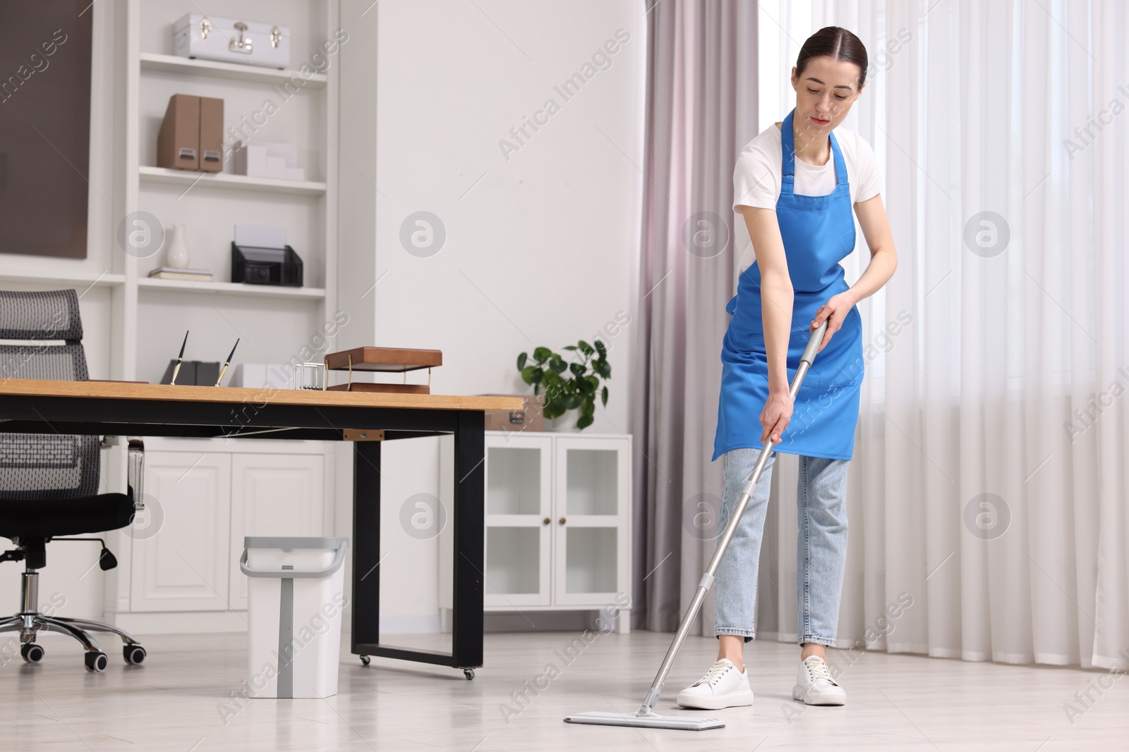 Photo of Cleaning service. Woman washing floor with mop in office