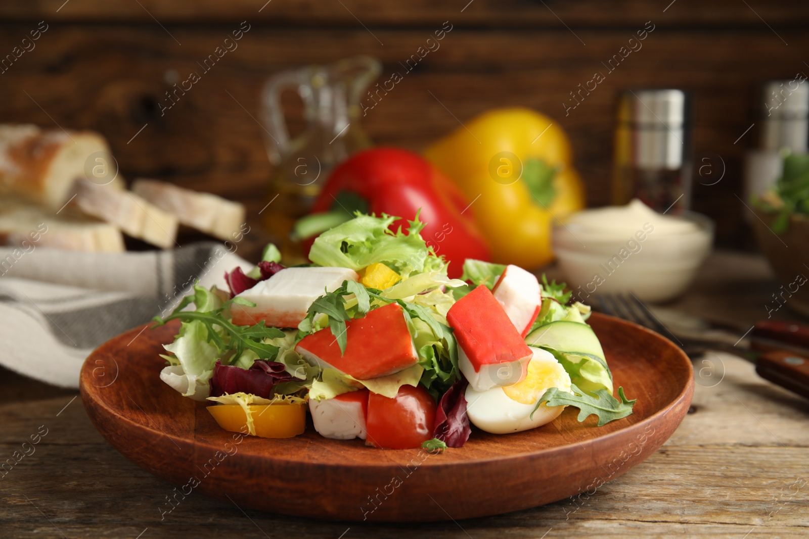 Photo of Delicious salad with crab sticks and lettuce on wooden table
