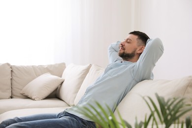 Photo of Man resting on comfortable sofa in living room