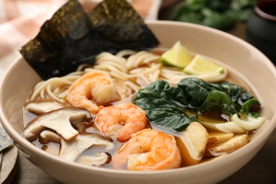Photo of Delicious ramen with shrimps and mushrooms in bowl on table, closeup. Noodle soup