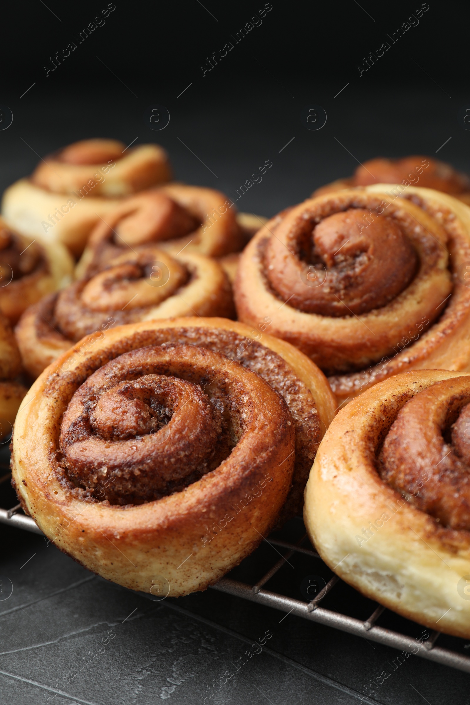 Photo of Tasty cinnamon rolls on black table, closeup