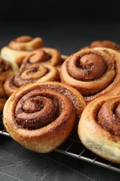 Tasty cinnamon rolls on black table, closeup