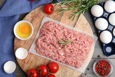 Photo of Raw chicken minced meat and ingredients on grey wooden table, flat lay