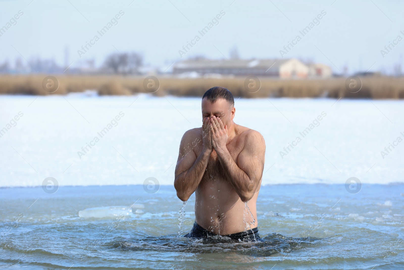 Photo of MYKOLAIV, UKRAINE - JANUARY 19, 2021: Man immersing in icy water on winter day. Traditional Baptism ritual